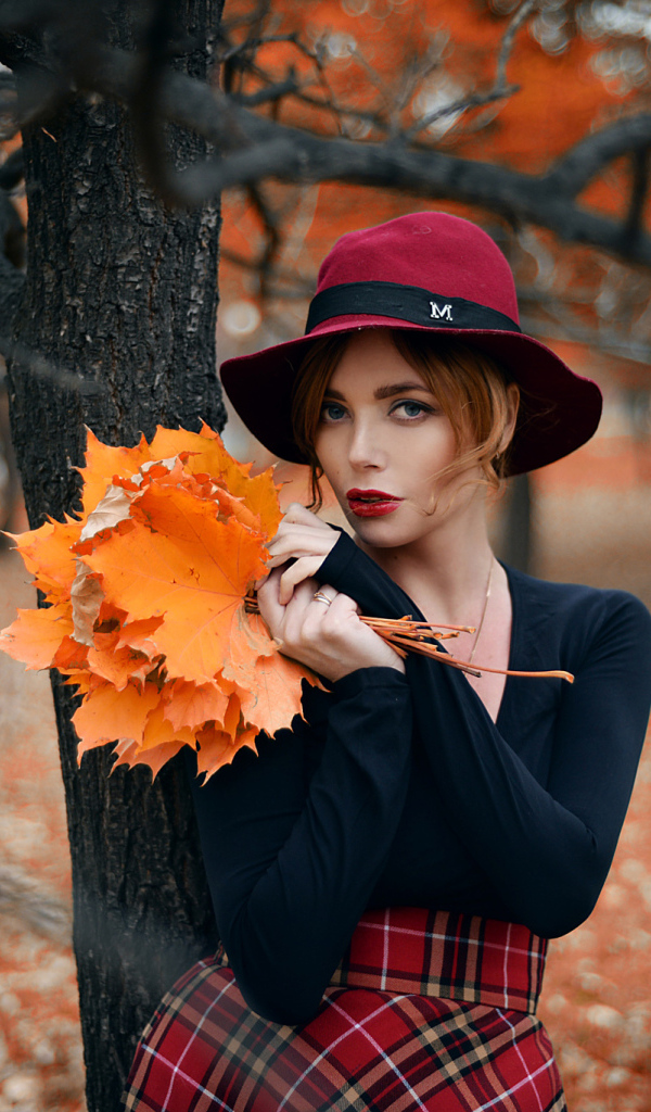 Девушка стоит у дереве с желтыми листьями осенью