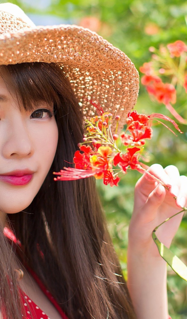 Девушка азиатка в шляпе с красным цветком