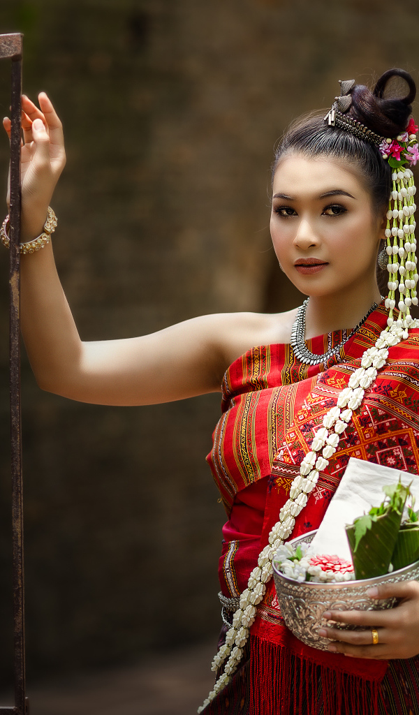 Девушка азиатка в костюме стоит у железных ворот