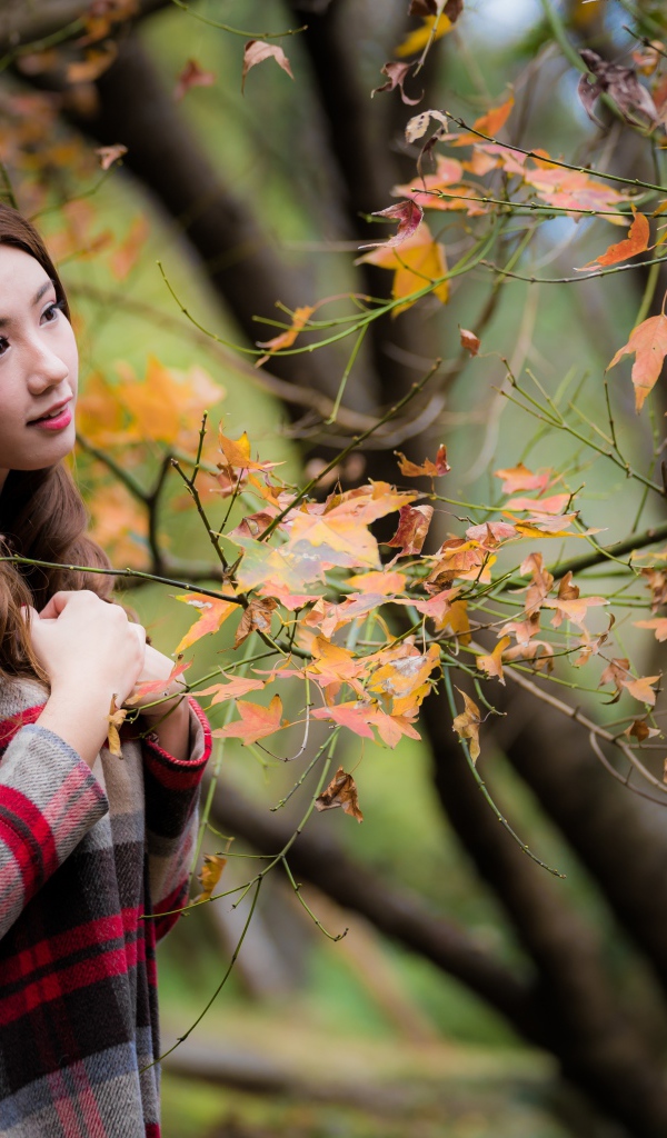 Красивая азиатка стоит у дерева