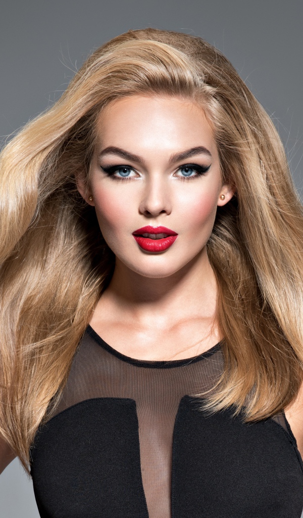 Красивая голубоглазая блондинка в черном платье на сером фоне