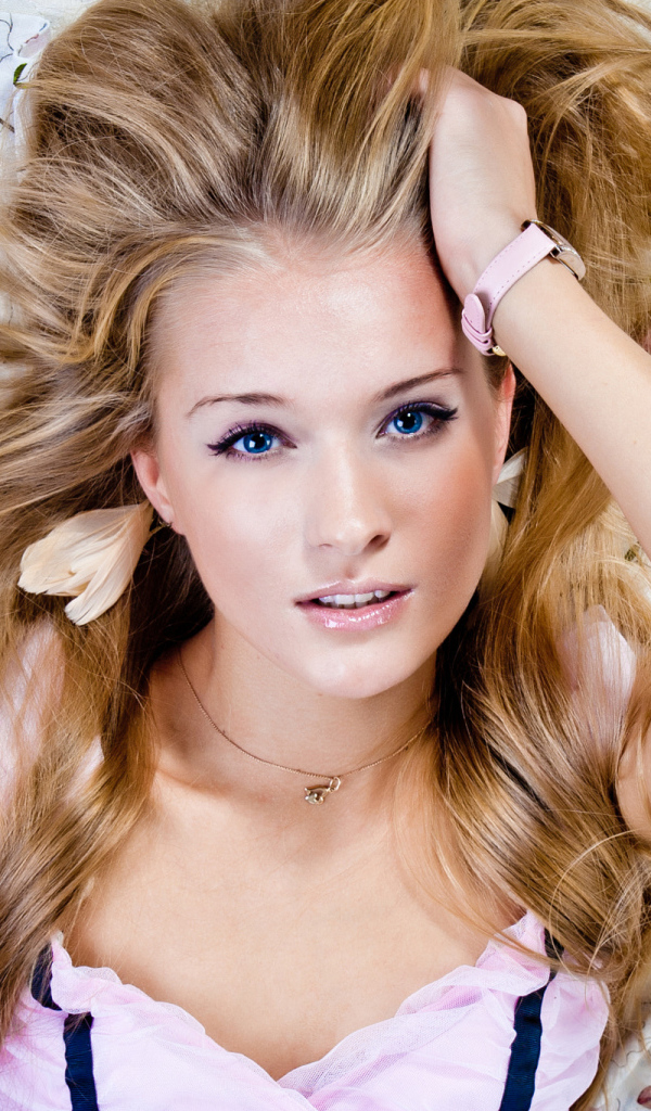 Красивая голубоглазая блондинка лежит на кровати 