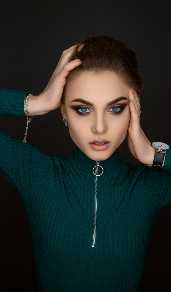 Красивая голубоглазая девушка в зеленом свитере на черном фоне