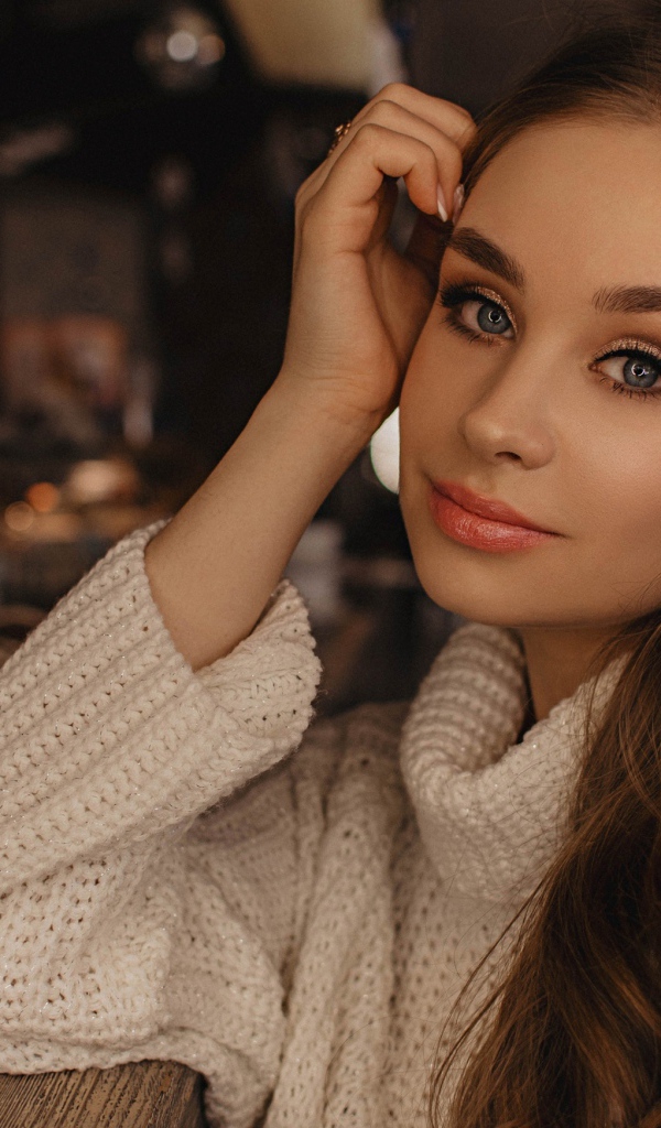 Красивая голубоглазая девушка в белом свитере в кафе