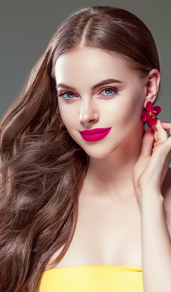 Красивая голубоглазая девушка с длинными волосами на сером фоне