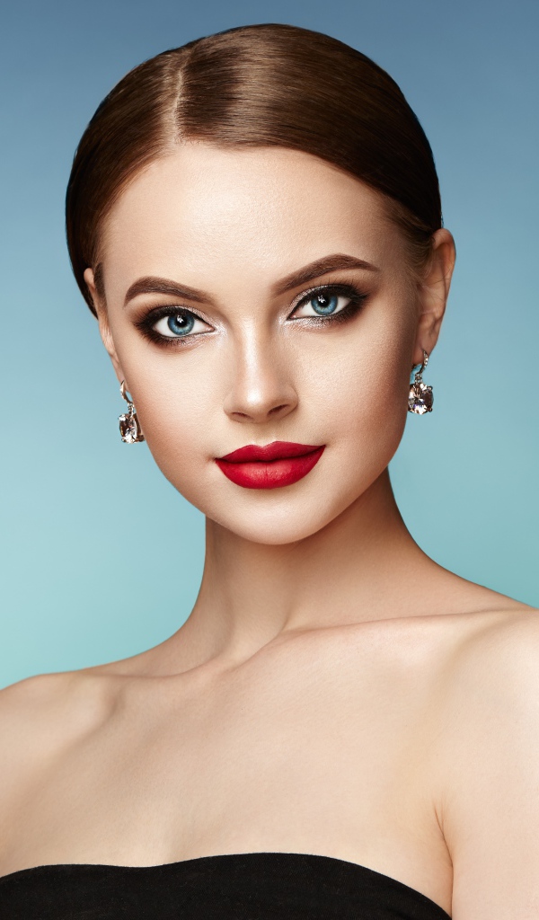 Красивая голубоглазая девушка с накрашенными губами и серьгами в ушах