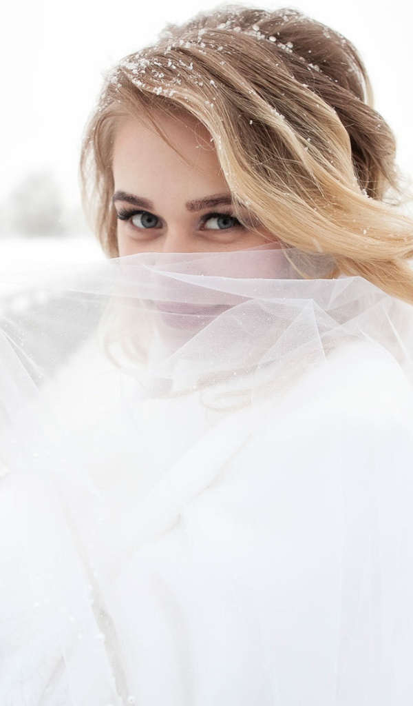 Красивая невеста с букетом в руках закрывает лицо фатой