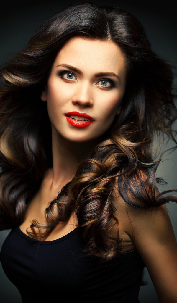 Красивая яркая девушка с длинными волосами на сером фоне