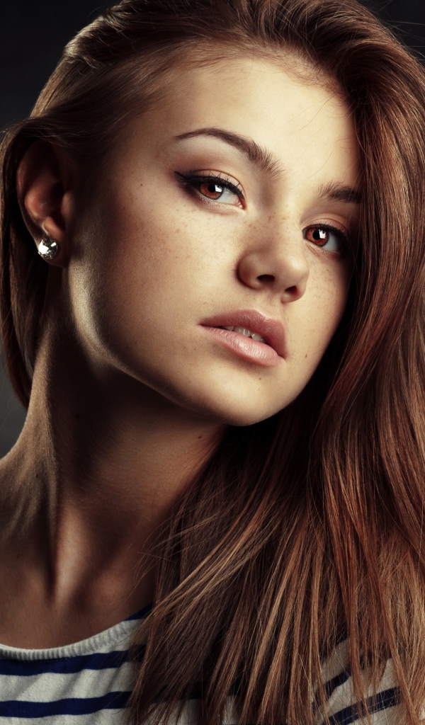 Красивая кареглазая девушка с русыми волосами на сером фоне