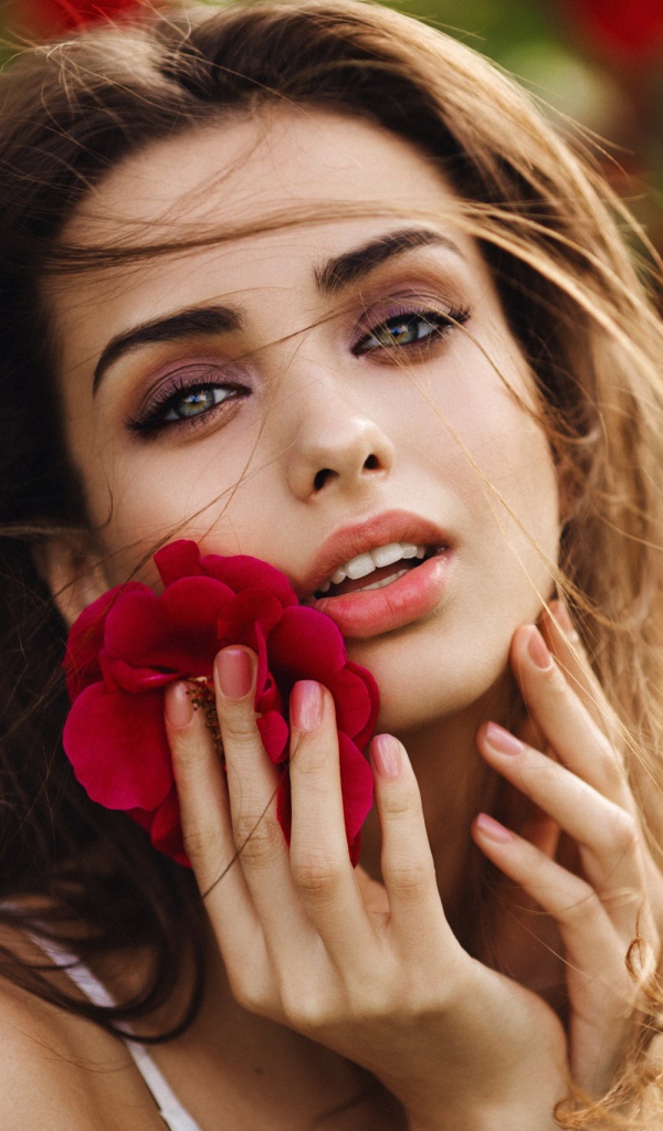 Красивая девушка шатенка с цветком у лица