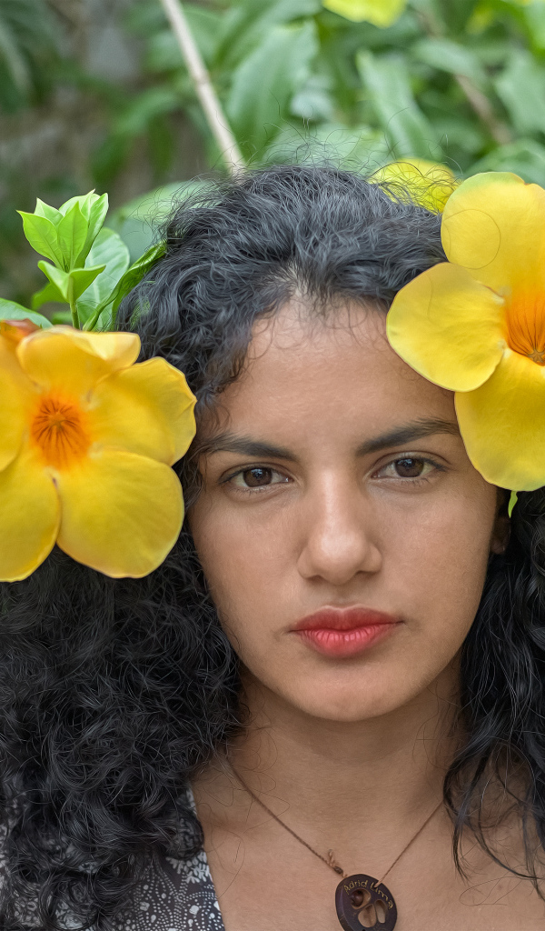 Красивая брюнетка с большими желтыми цветами в волосах 
