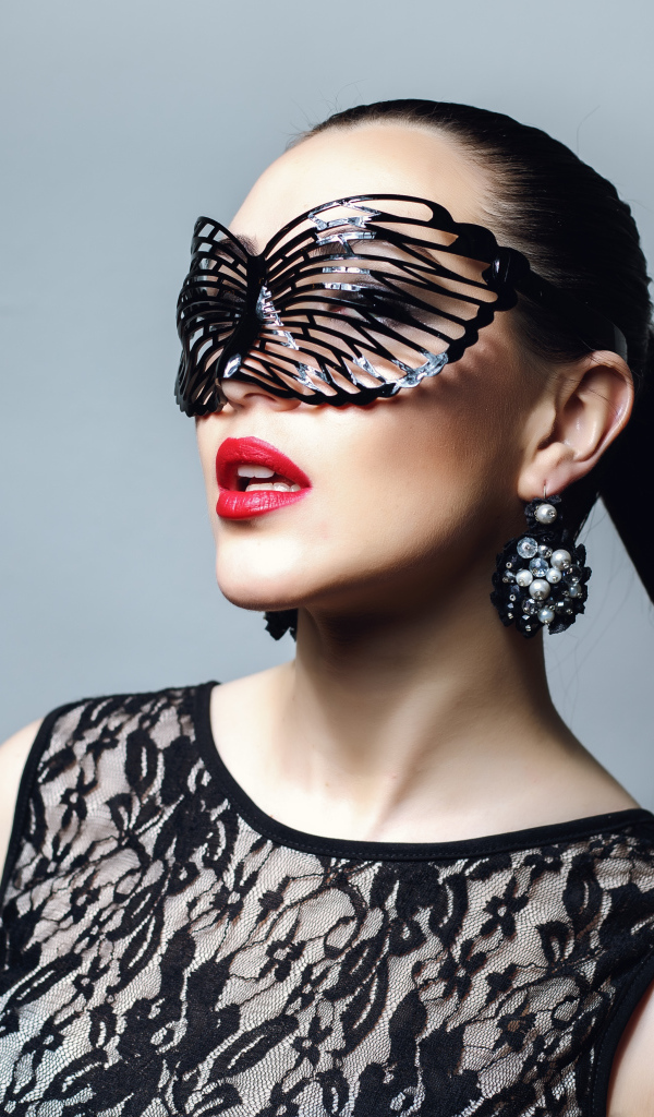 Красивая модная девушка в черной маске на сером фоне