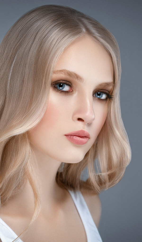 Красивая нежная голубоглазая блондинка на сером фоне