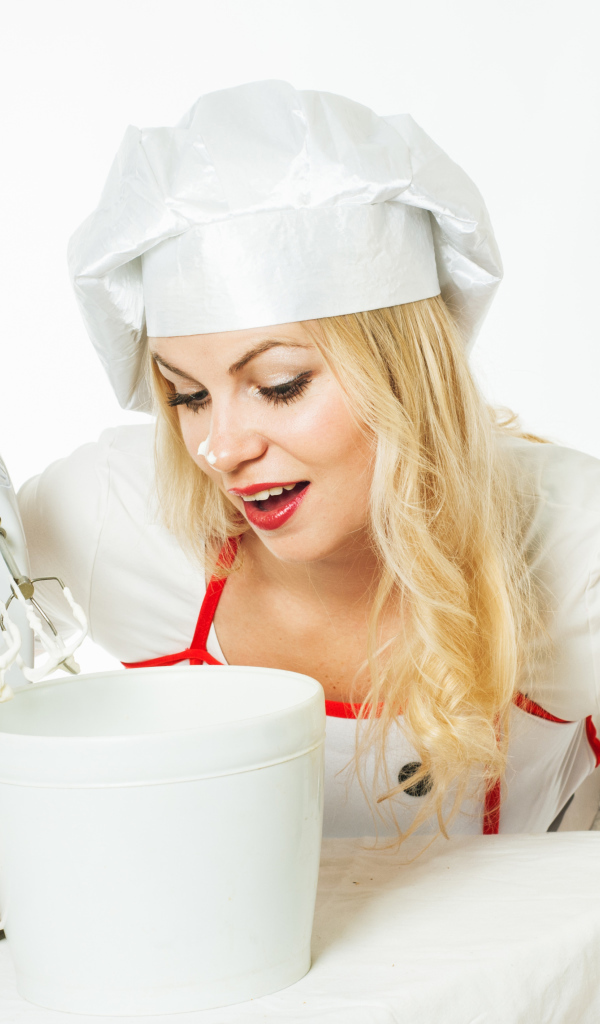 Красивая девушка повар взбивает крем для торта миксером