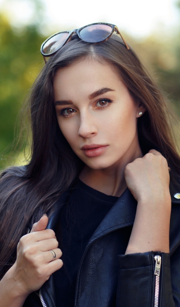 Красивая девушка в черной куртке с очками на голове