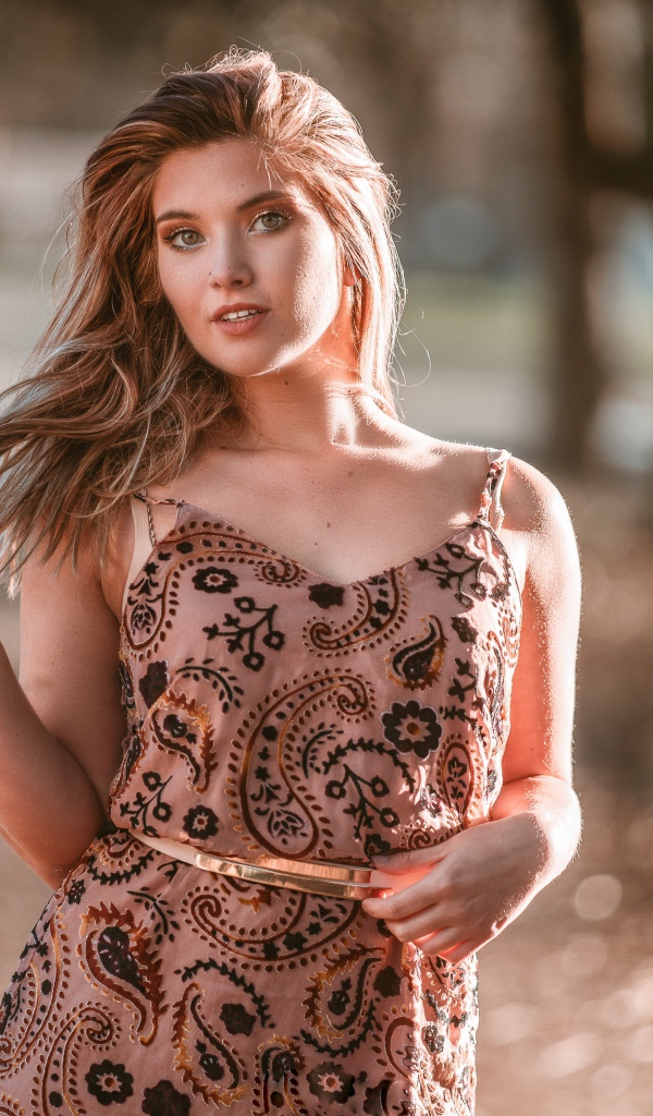 Красивая девушка в платье в лучах солнца летом