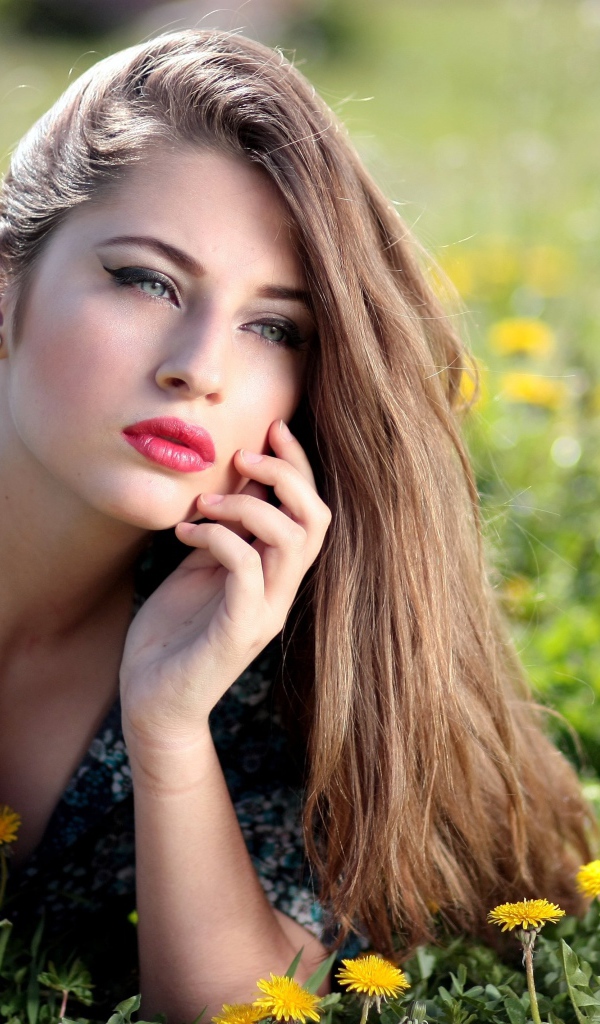 Красивая девушка в платье лежит на траве с одуванчиками