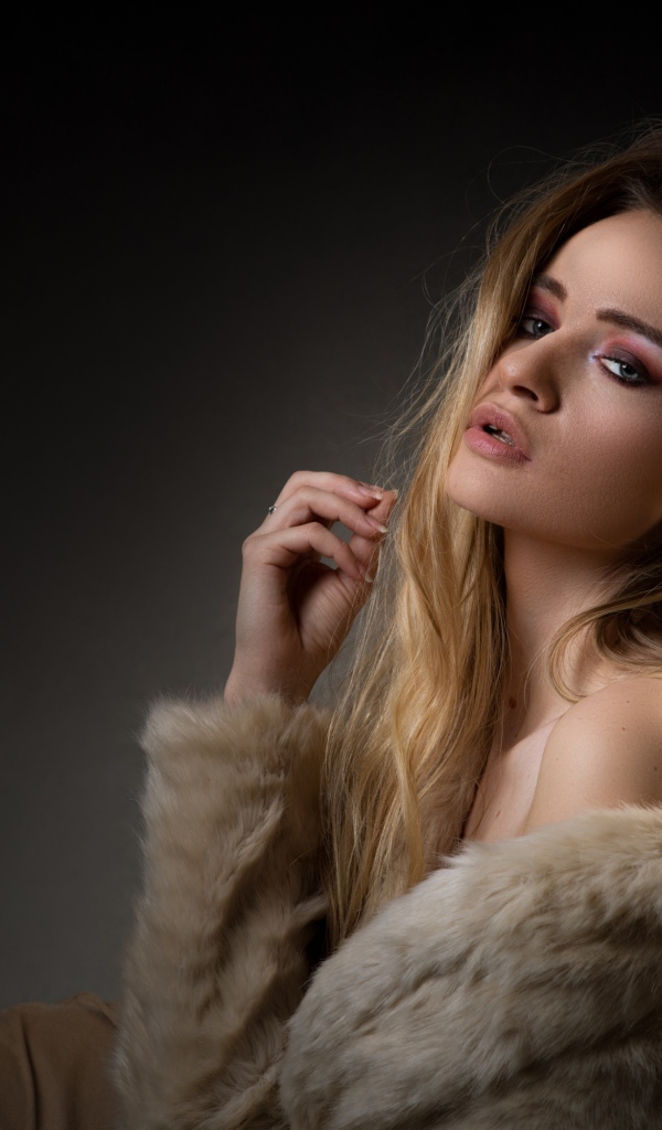 Beautiful girl in a fur coat on a gray background