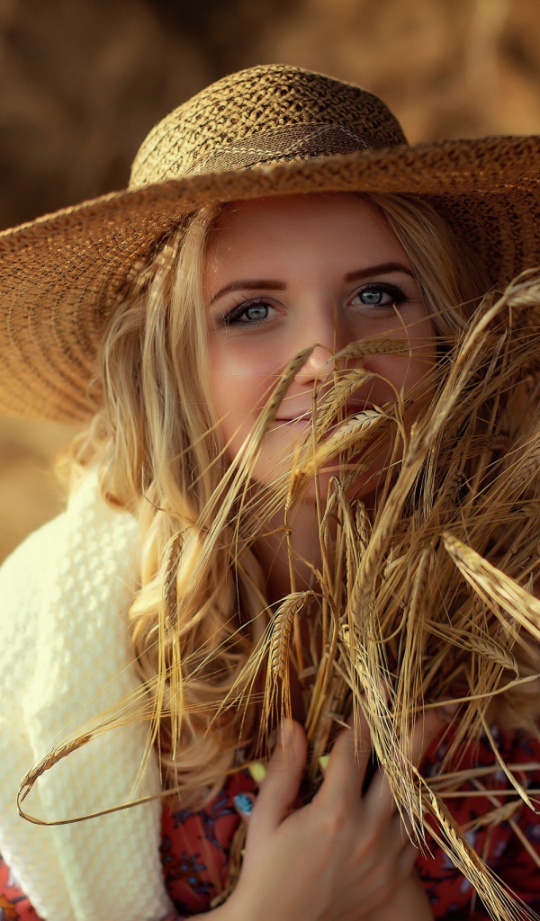 Красивая девушка в шляпе с колосьями в руке