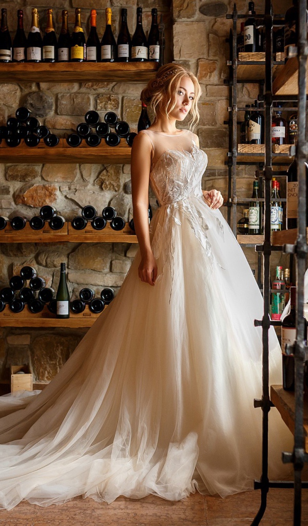Красивая девушка в пышном свадебном платье в винном погребе