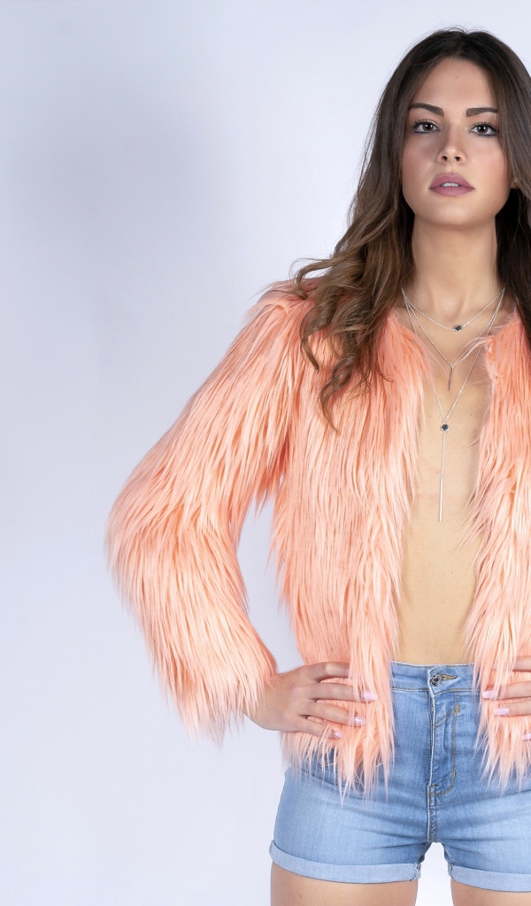 Красивая девушка в розовой шубе и джинсовых шортах