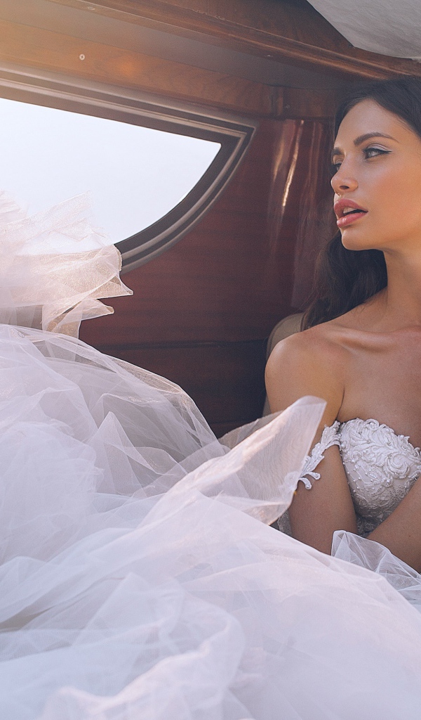 Красивая девушка в белом свадебном платье в машине