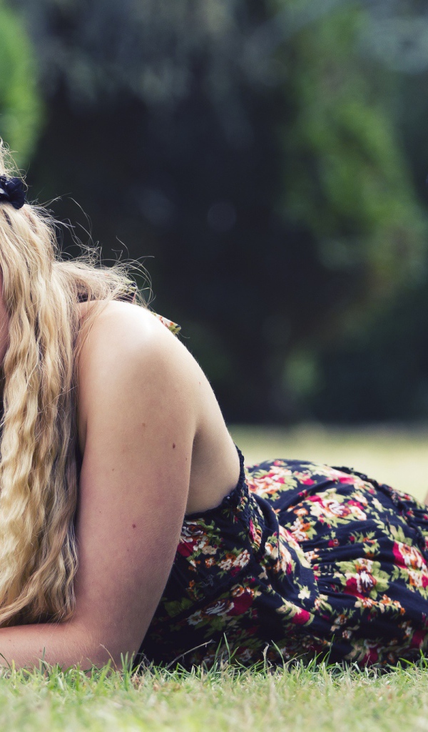 Красивая девушка в черных туфлях лежит на зеленой траве