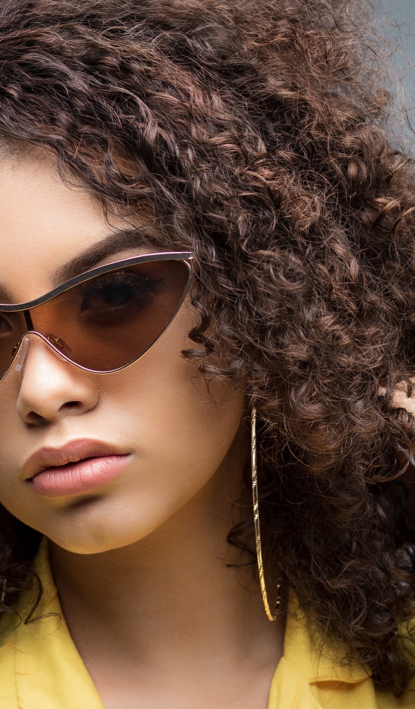 Красивая девушка в солнечных очках на сером фоне