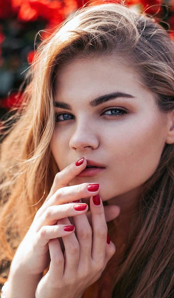 Красивая девушка на фоне красных цветов