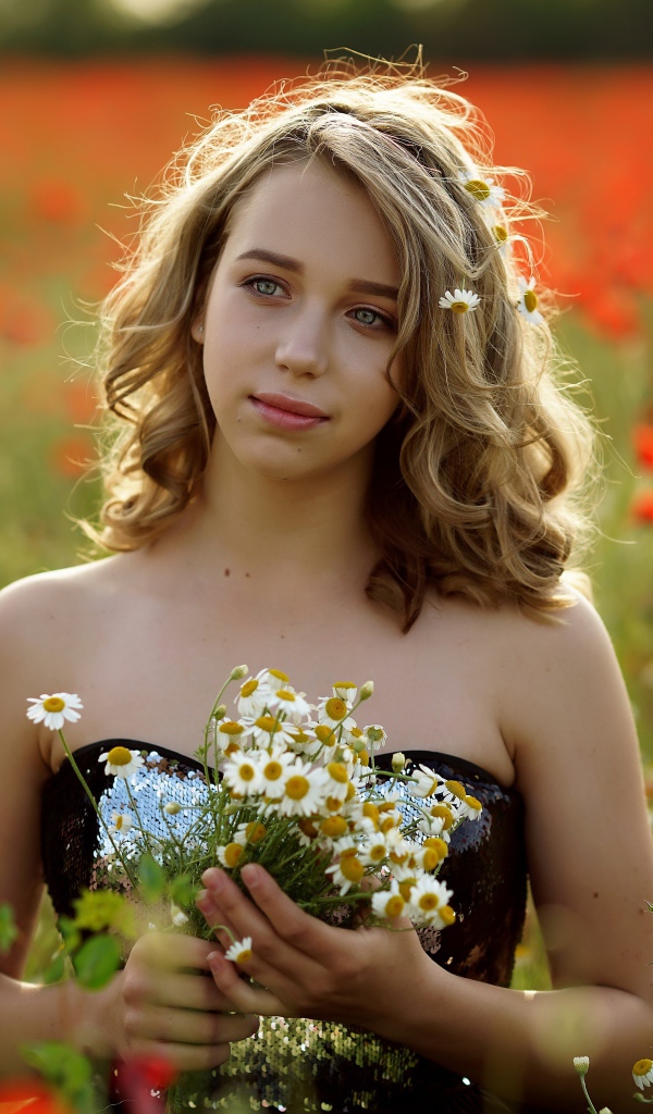Красивая девушка с букетом ромашек на поле с маками