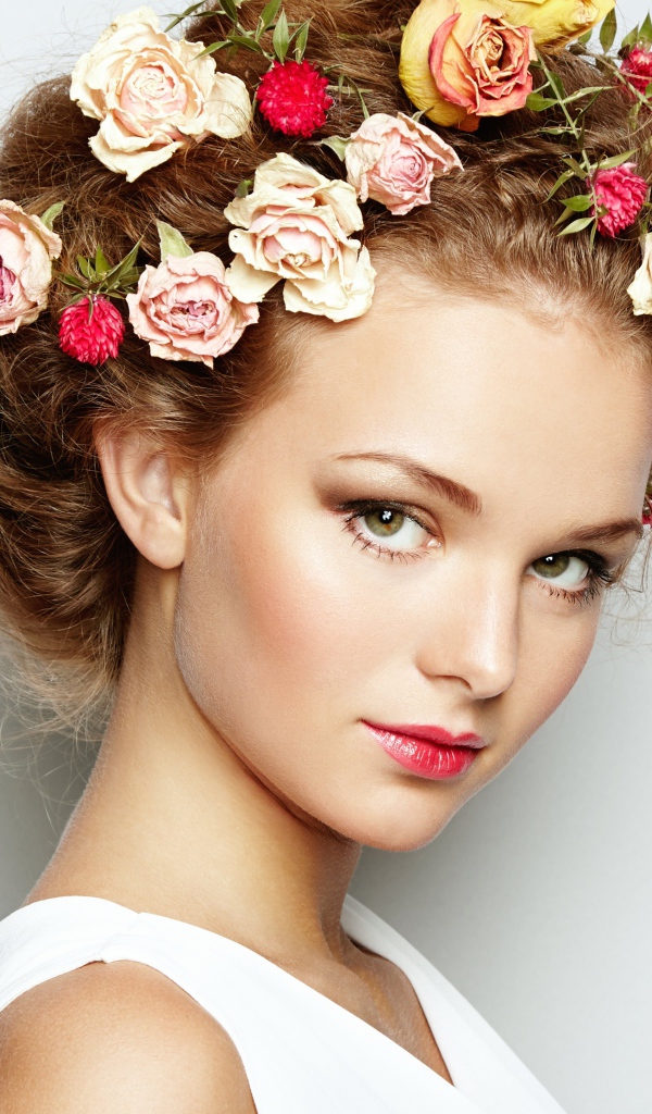 Красивая девушка с цветами в волосах на сером фоне