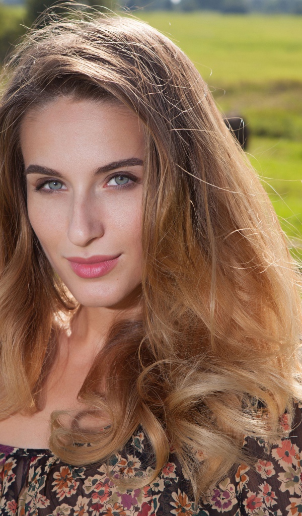 Красивая девушка с серыми глазами стоит у сена