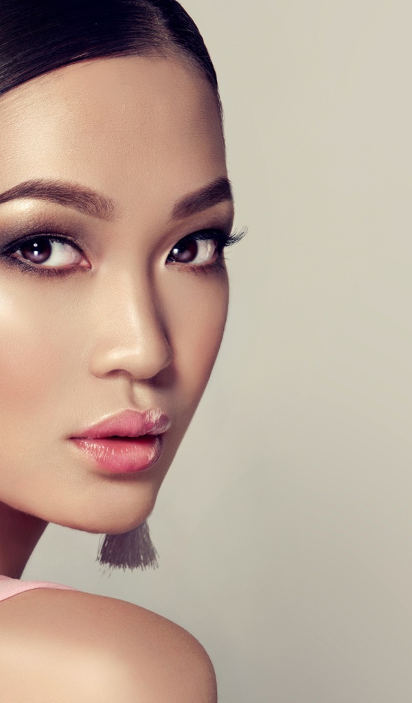 Красивая девушка с прической и сережками в ушах на сером фоне