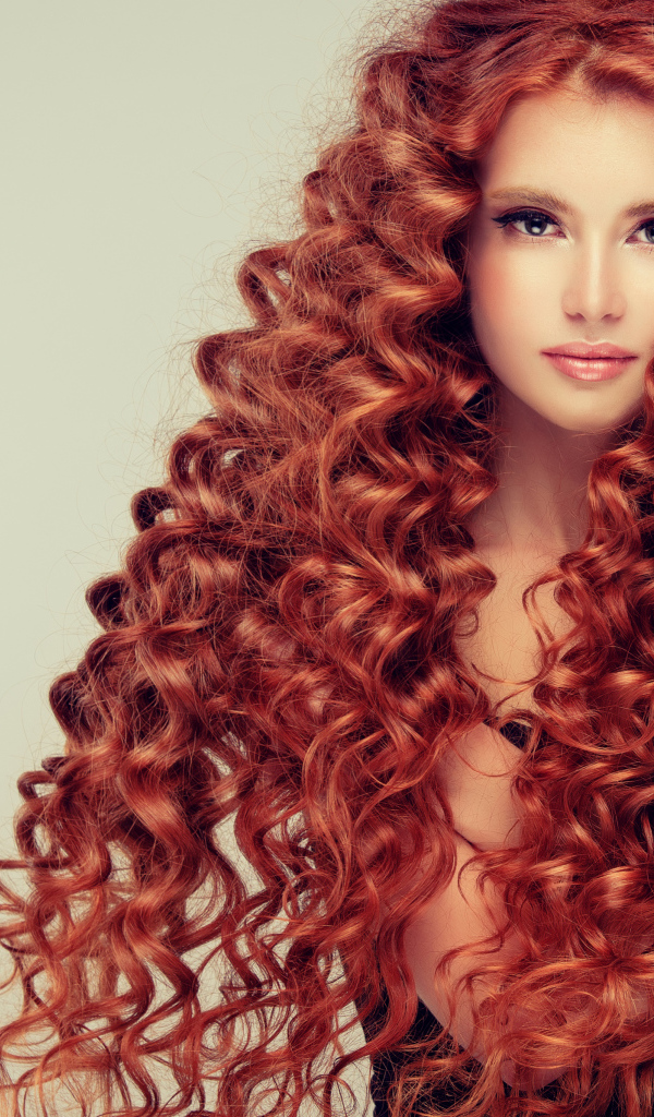 Красивая девушка с длинными рыжими волосами на сером фоне