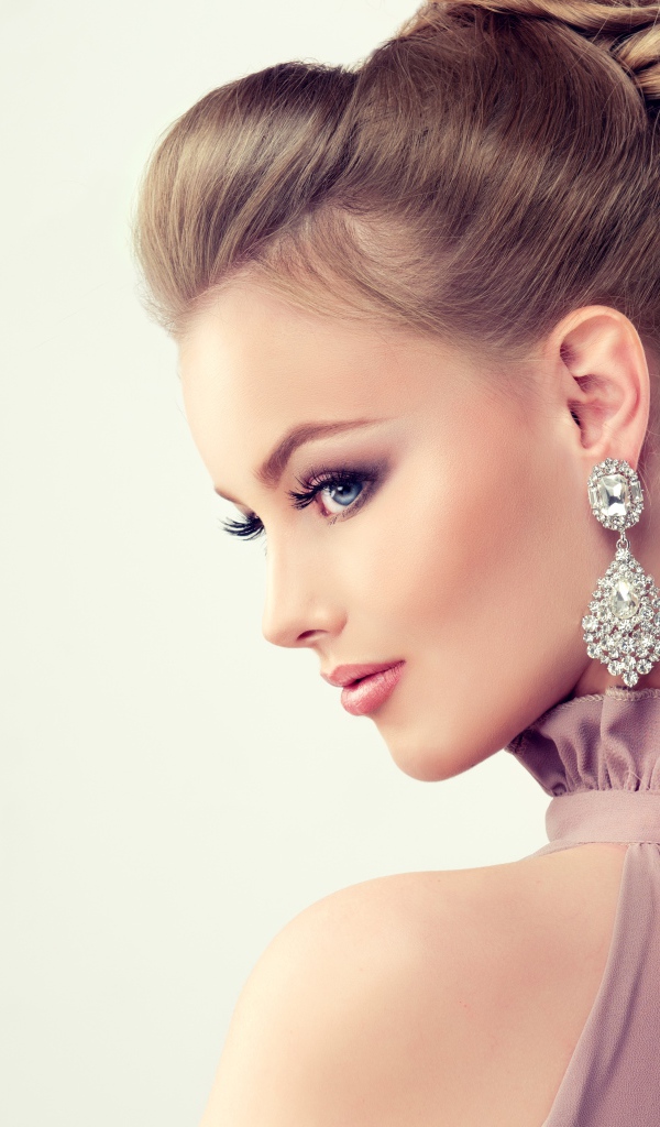 Красивая девушка с макияжем и прической на сером фоне