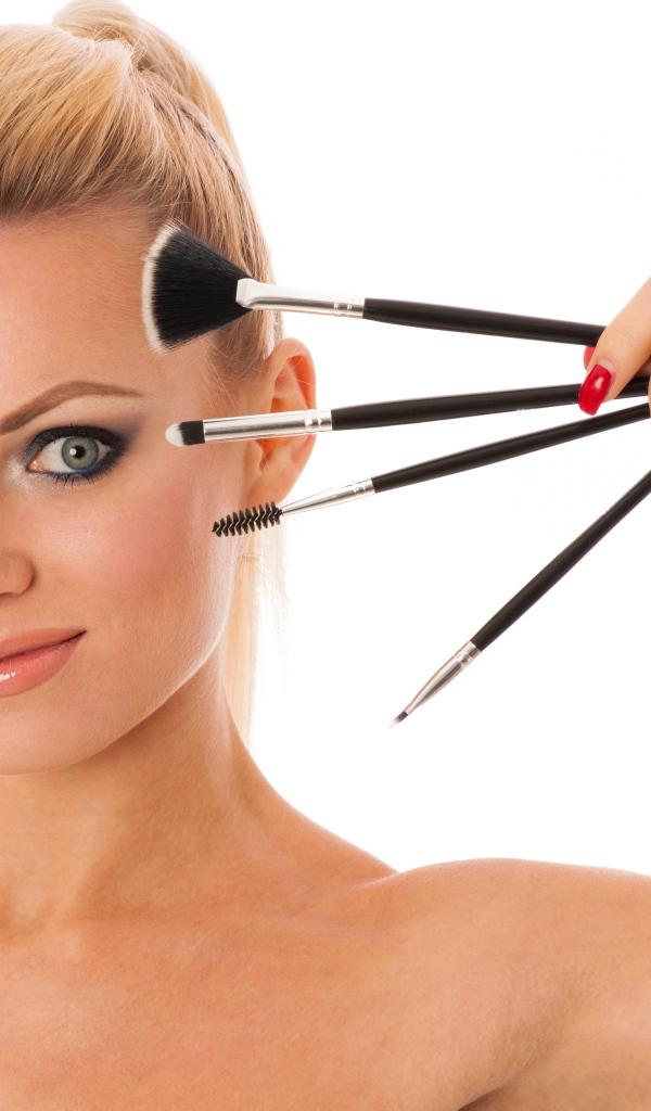 Красивая девушка с кистями для макияжа на белом фоне