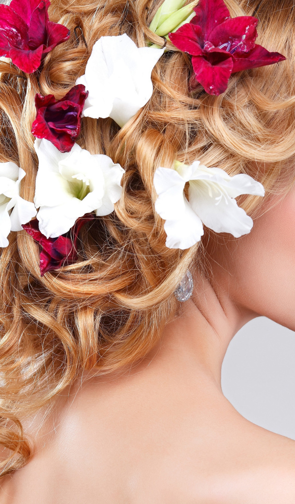 Красивая девушка с цветами петунии в волосах на сером фоне