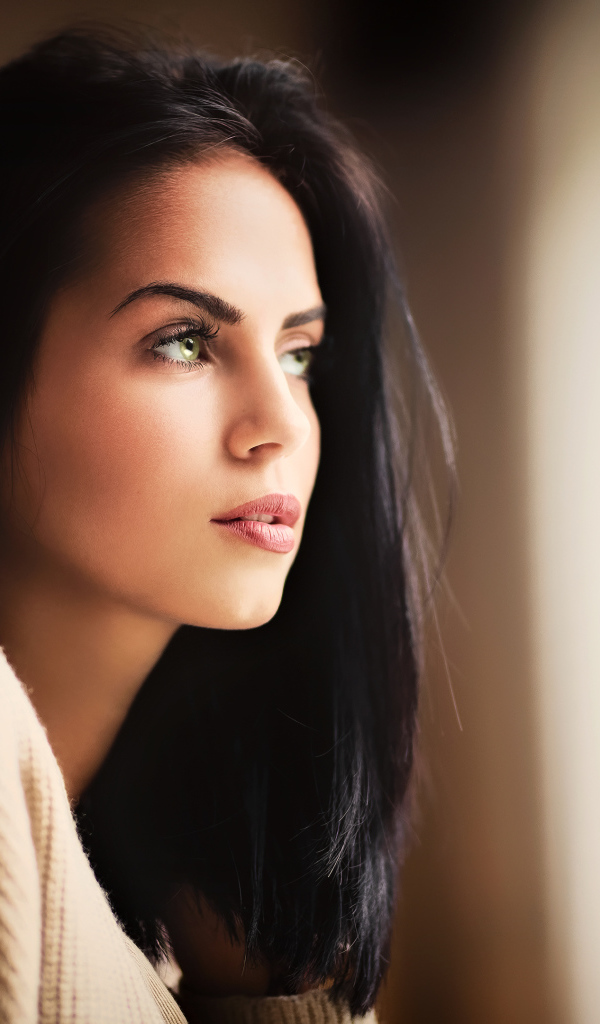 Красивая девушка зеленоглазая смотрит в окно 