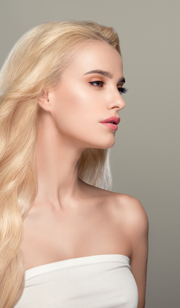 Красивая длинноволосая девушка блондинка на сером фоне