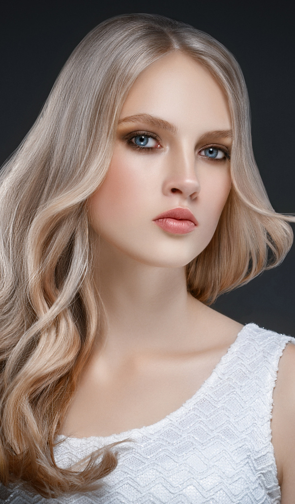 Красивая длинноволосая блондинка с голубыми глазами на сером фоне