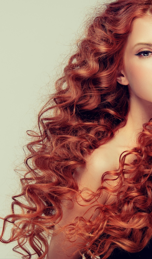 Красивая рыжеволосая девушка на сером фоне