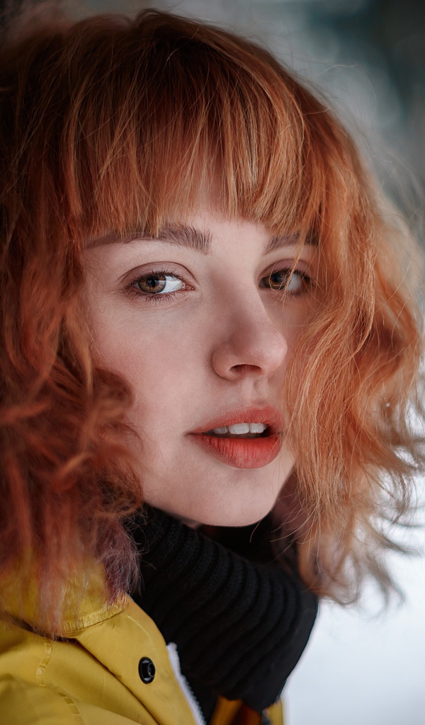 Красивая рыжеволосая девушка стоит у дерева зимой