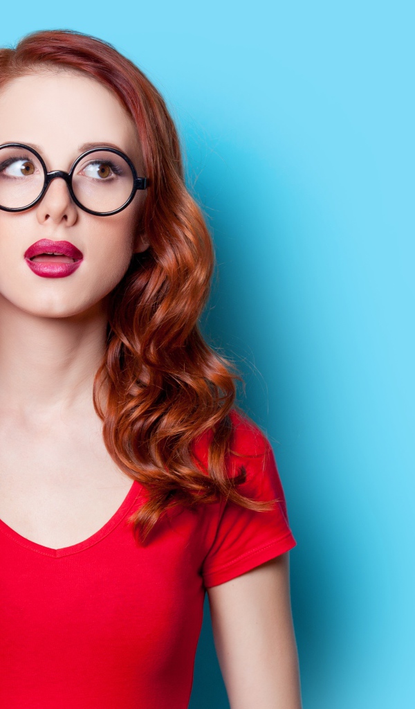 Красивая рыжеволосая девушка в очках на голубом фоне