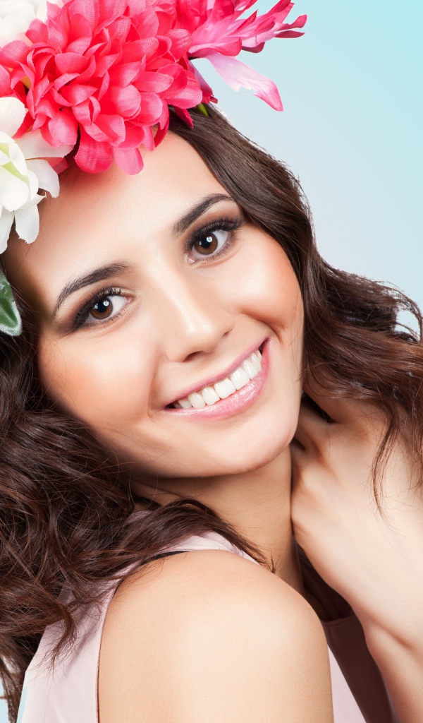 Красивая улыбающаяся девушка с венком на голове на голубом фоне