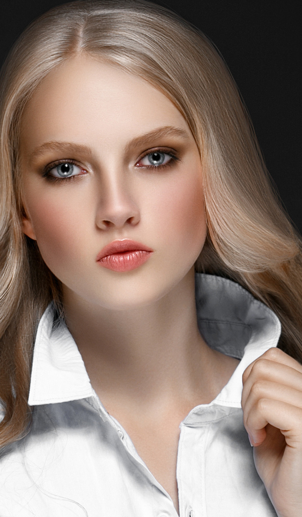 Красивая стильная голубоглазая блондинка в белой рубашке на сером фоне