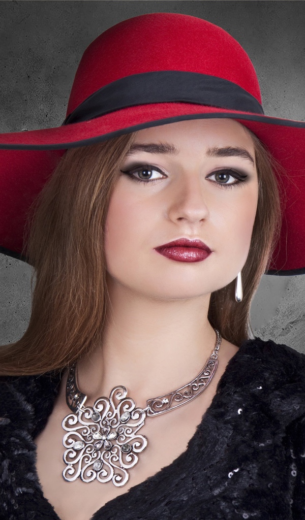 Красивая стильная девушка в красной шляпе с украшением на шее 