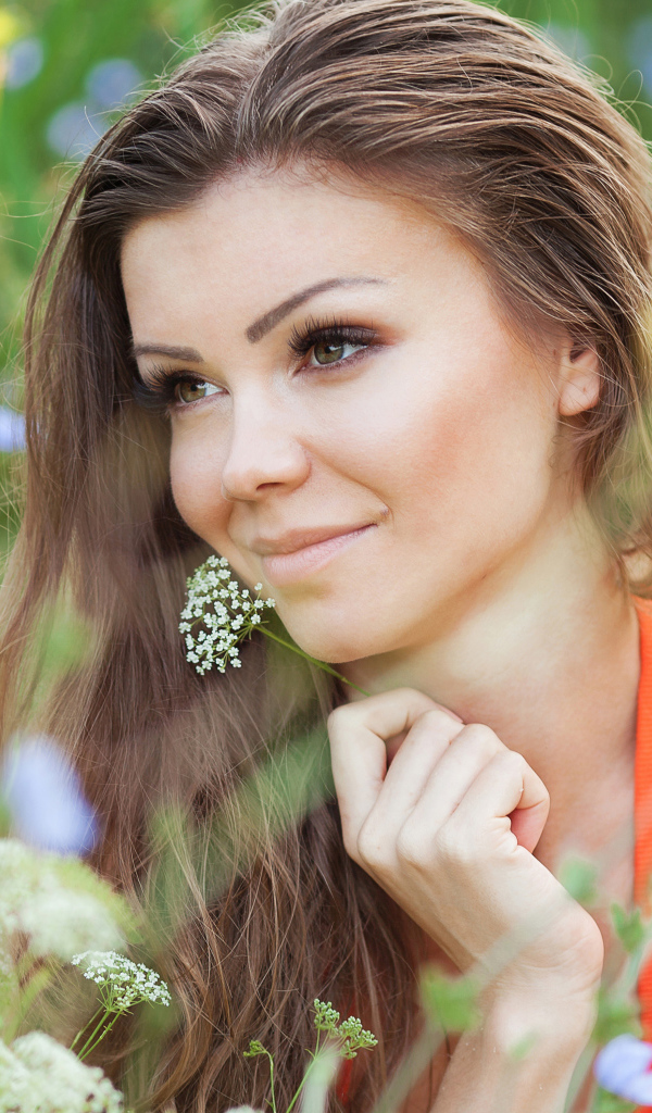 Красивая нежная девушка лежит в цветах на поле