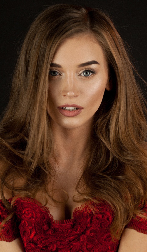 Красивая нежная длинноволосая шатенка в красном платье на черном фоне