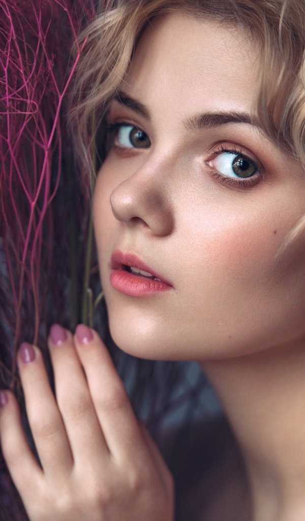 Красивая молодая блондинка с красным растением в руках