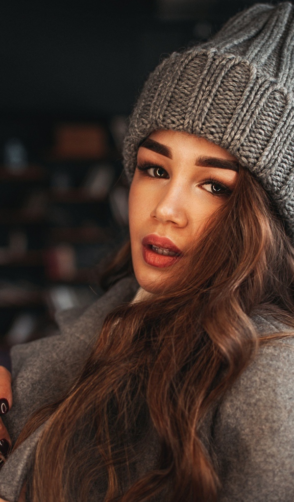 Красивая молодая девушка в пальто в вязаной шапке